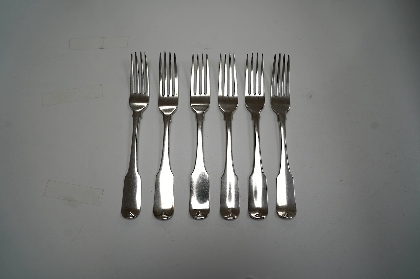 A set of four George III Irish silver fiddle pattern table forks, maker JS, Dublin, 1804, 20.9cm and a similar later pair, 12.8oz. Condition - poor to fair